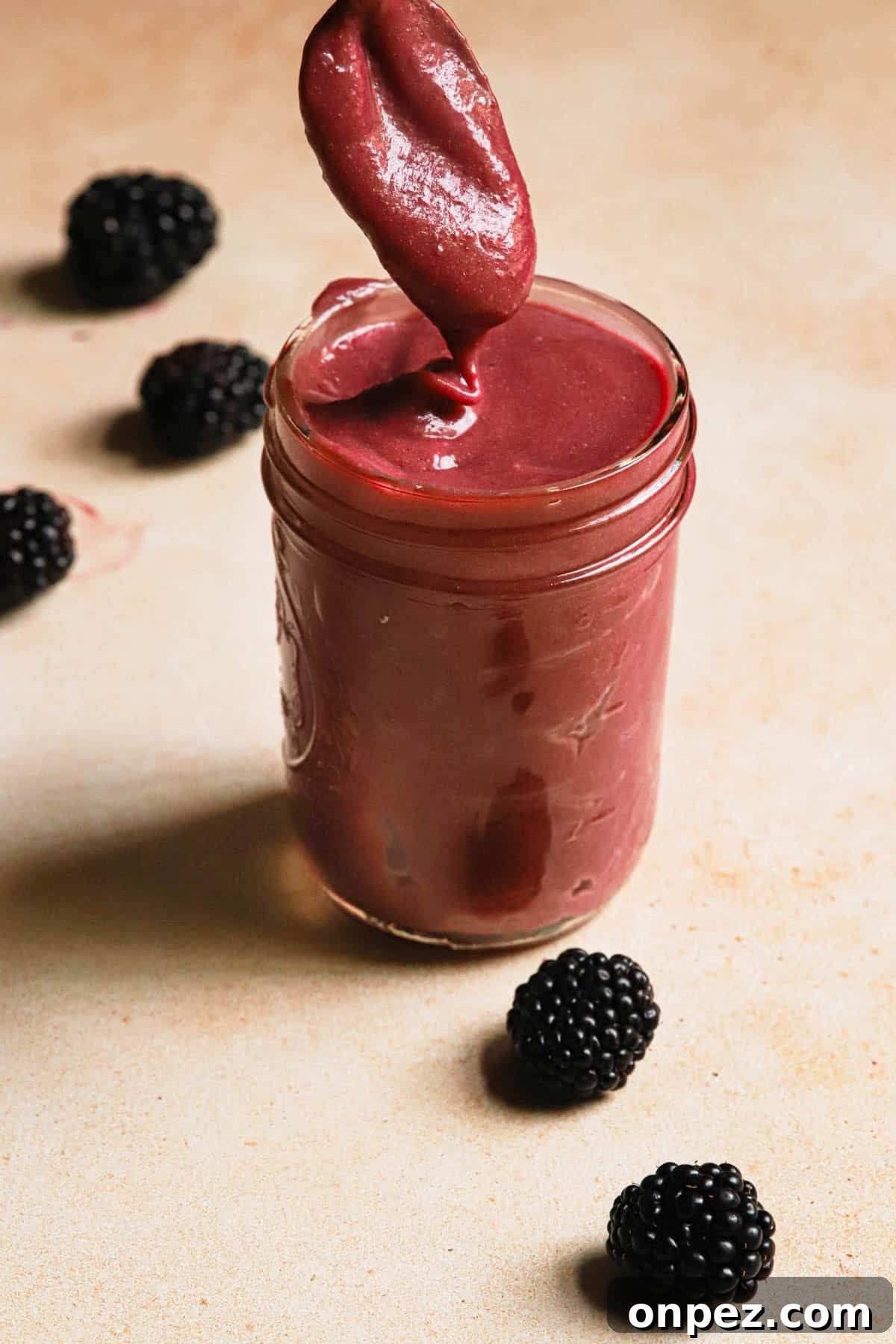 A spoon dipped into pink blackberry curd.