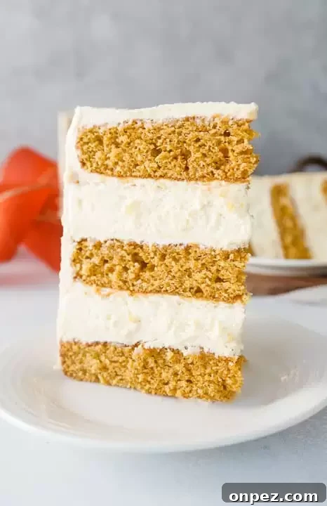Decadent Pumpkin Cheesecake Layer Cake with Caramel Frosting 5 slice of pumpkin cheesecake layer cake on a plate with another slice in the background