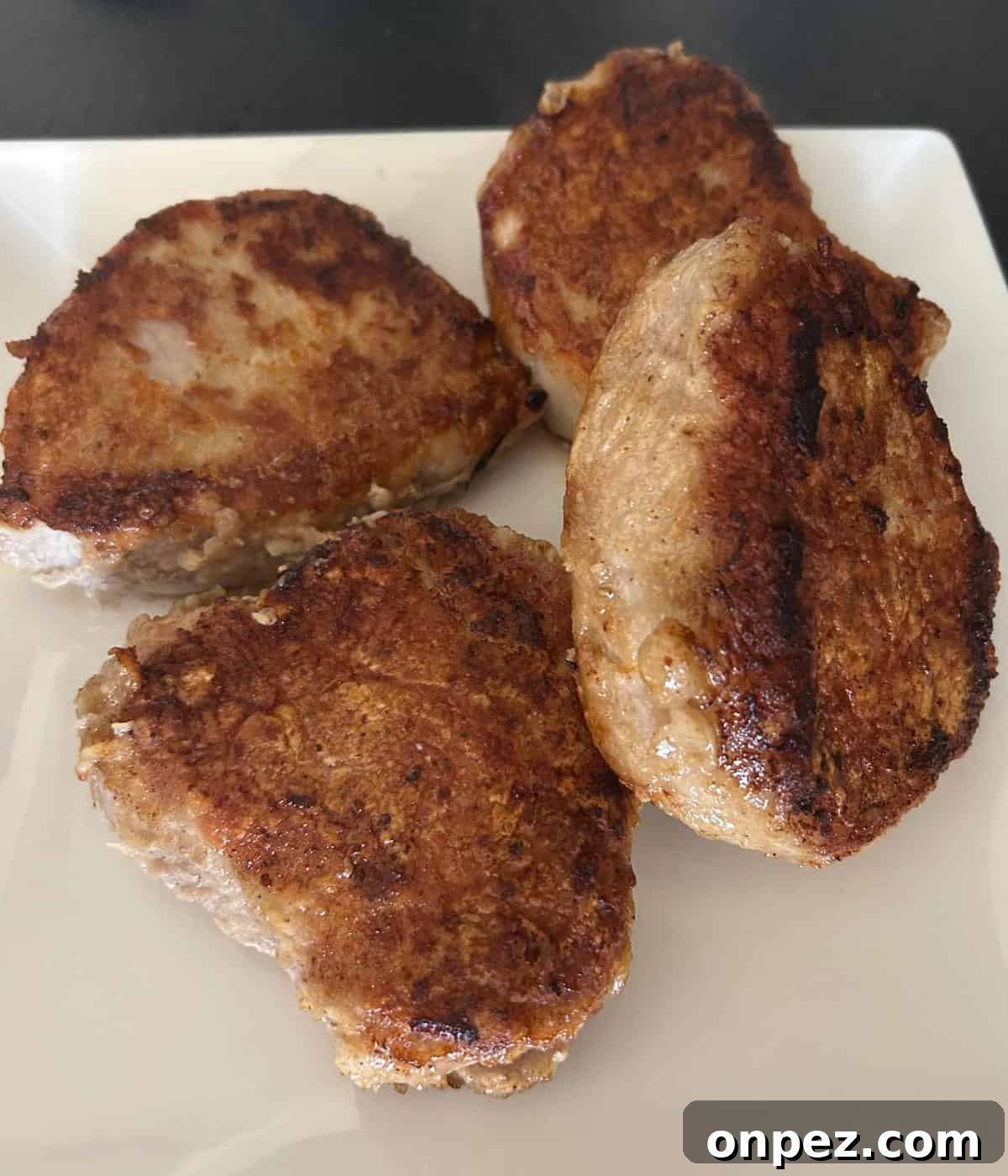Dutch Oven Pork Chops with Tender Gravy 7 Pan fried boneless pork chops on plate.