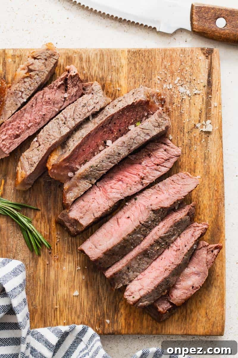 New york strip steak on a cutting board with a knife and rosemary.