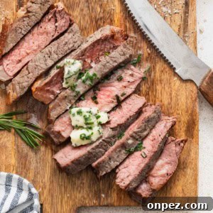 Air fryer New York strip steak sliced on a cutting board and topped with a melted compound butter.