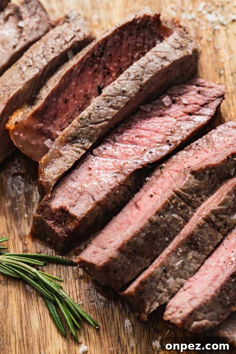 Cooked NY strip steak sliced and topped with flakes of sea salt and rosemary.