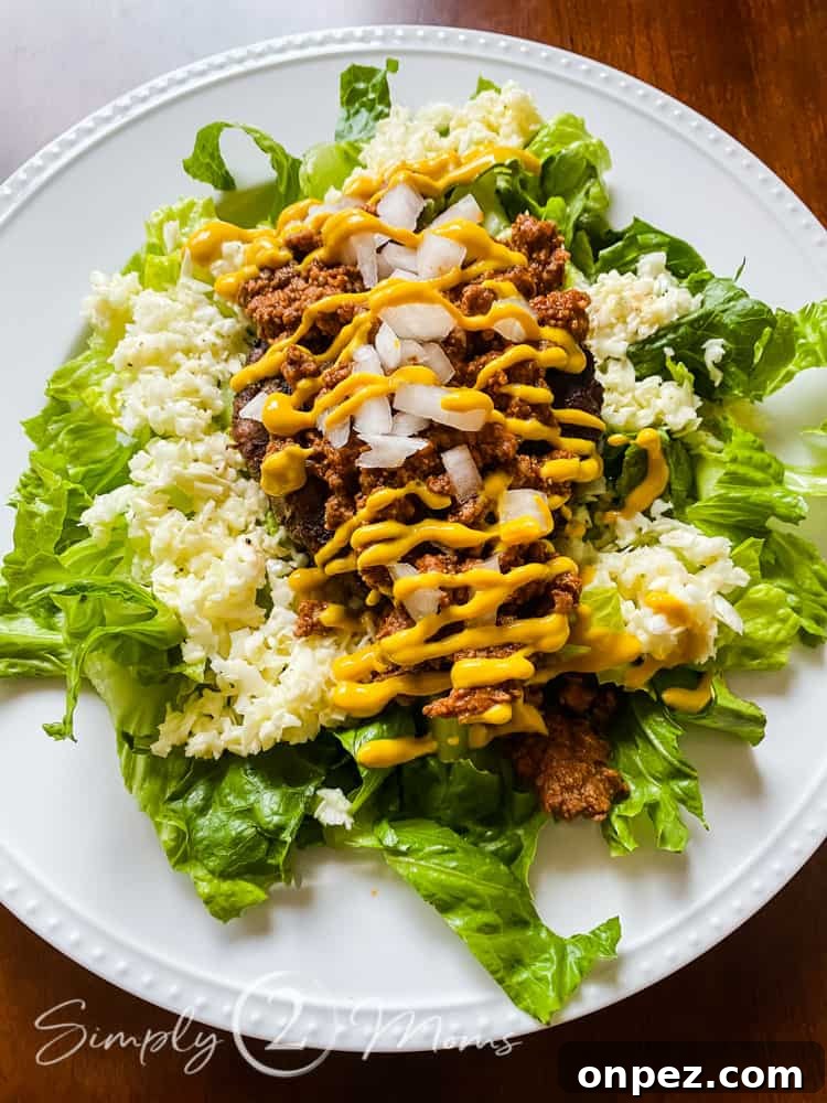 Skip the bun with this healthy summer salad made of torn Romaine lettuce topped with low carb coleslaw, a hotdog, hotdog chili, diced onions, with a drizzle of yellow mustard