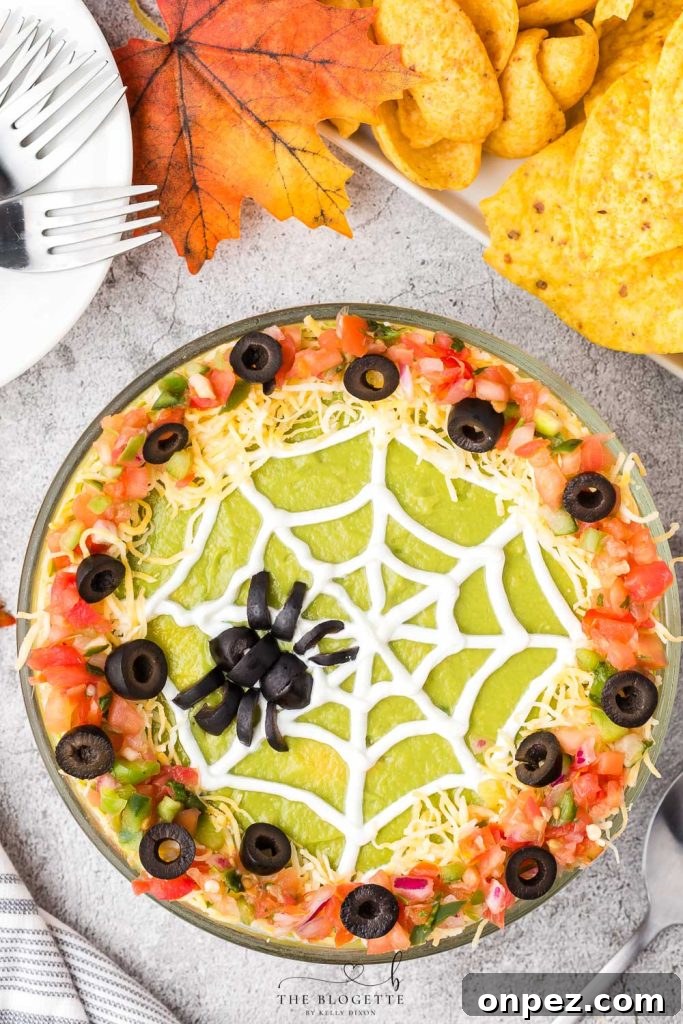 Spider Web 7 Layer Dip is just what your Halloween needs! A spooky little olive spider sits atop a sour cream spider web on layers of meat, beans, cheese, guacamole, and more!
