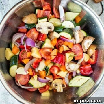 Assorted chopped vegetables in a stainless steel bowl viewed from above.