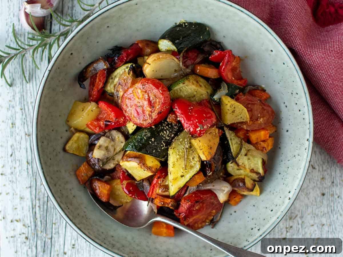 Assorted colorful chopped and roasted vegetables in a pale green bowl viewed from above.
