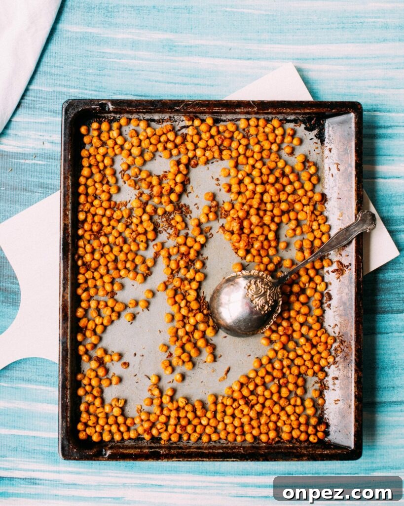 Spicy Vegan Buffalo Chickpea Wrap Recipe 7 Crispy roasted chickpeas on a baking sheet with a spoon