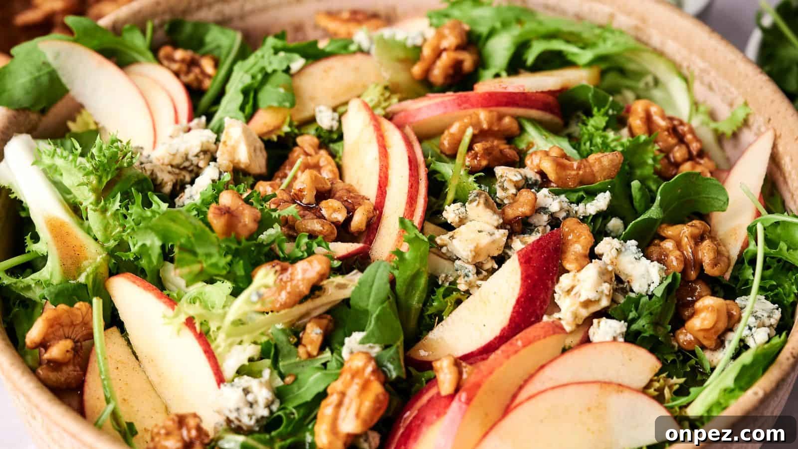 A bowl of mixed greens salad with sliced Honeycrisp apples, walnuts, and crumbled blue cheese.