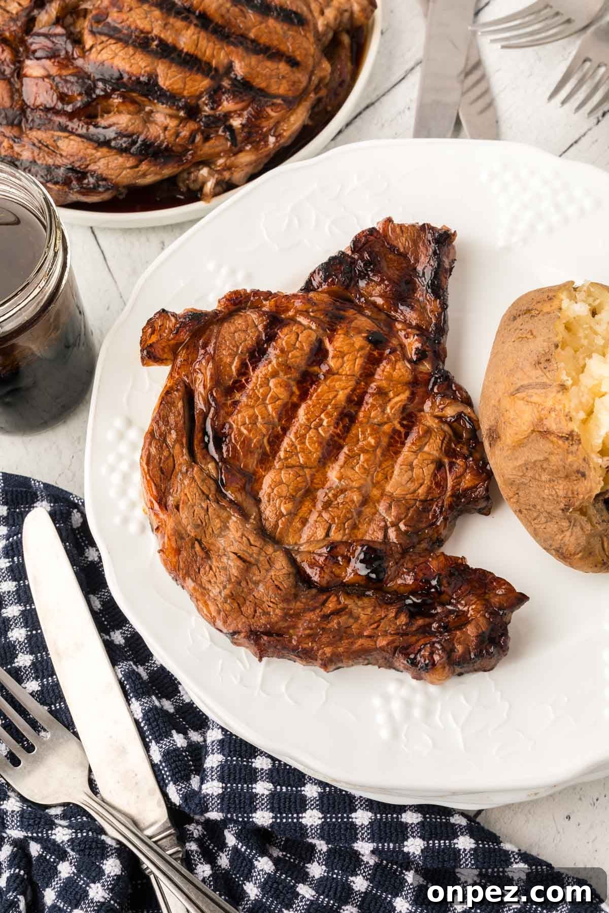 3-Ingredient Steak Marinade for Juicy, Tender Steaks 7 Grilled steak on a plate with a baked potato.