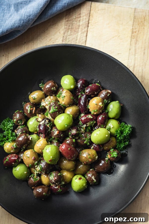 Garlic and Herb Marinated Olives Recipe 6 Green and black marinated olives with herbs, spices, garlic, oil and vinegar with parsley in a black bowl