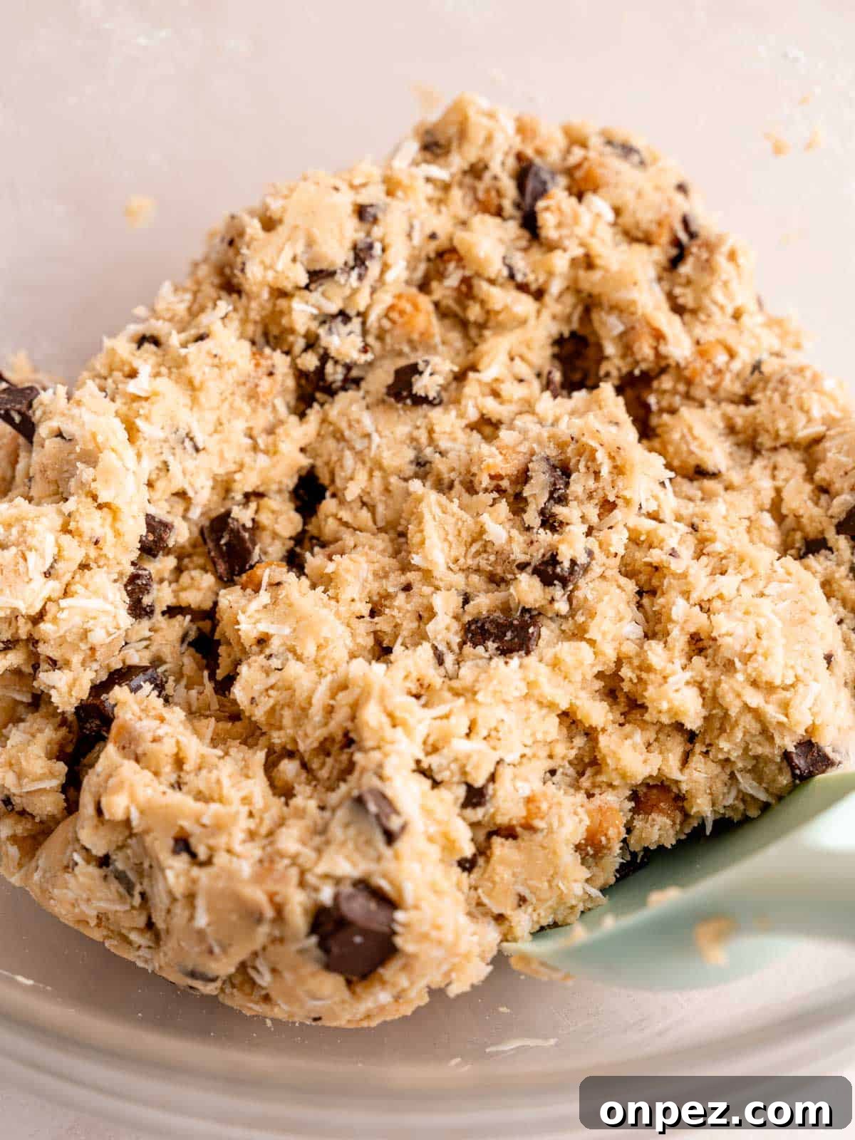 Levain Bakery Copycat Caramel Coconut Chocolate Chip Cookies 7 Cookie dough with shredded coconut, caramel bits, and chocolate chunks in a bowl.