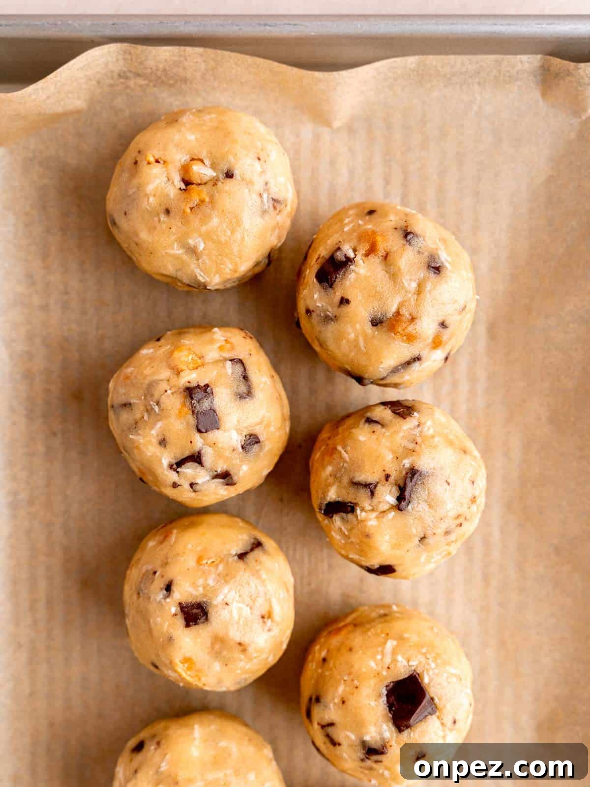 Levain Bakery Copycat Caramel Coconut Chocolate Chip Cookies 8 Large cookie dough balls on a parchment paper lined baking sheet.