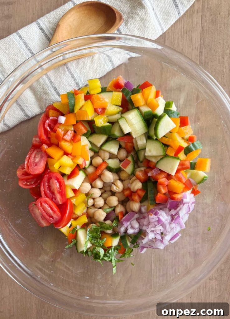 Mediterranean Chickpea Salad Recipe with Lemon and Herbs 5 chopped vegetables and chickpeas in large bowl