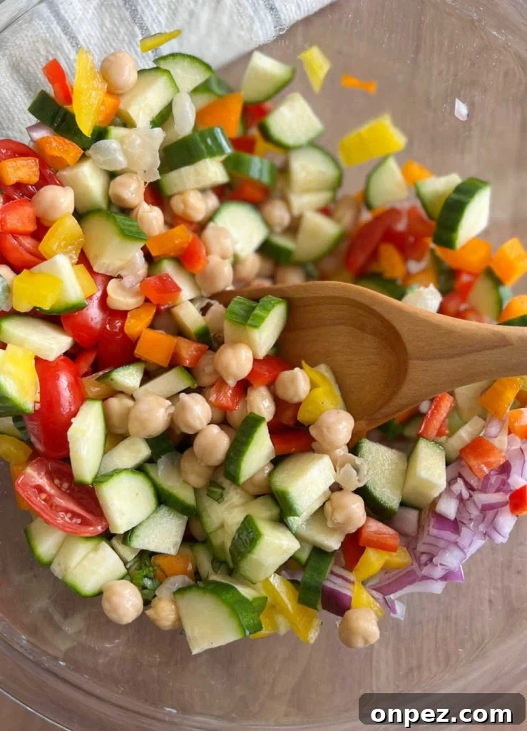 Mediterranean Chickpea Salad Recipe with Lemon and Herbs 6 mix garbanzo beans and salad ingredients with wooden spoon