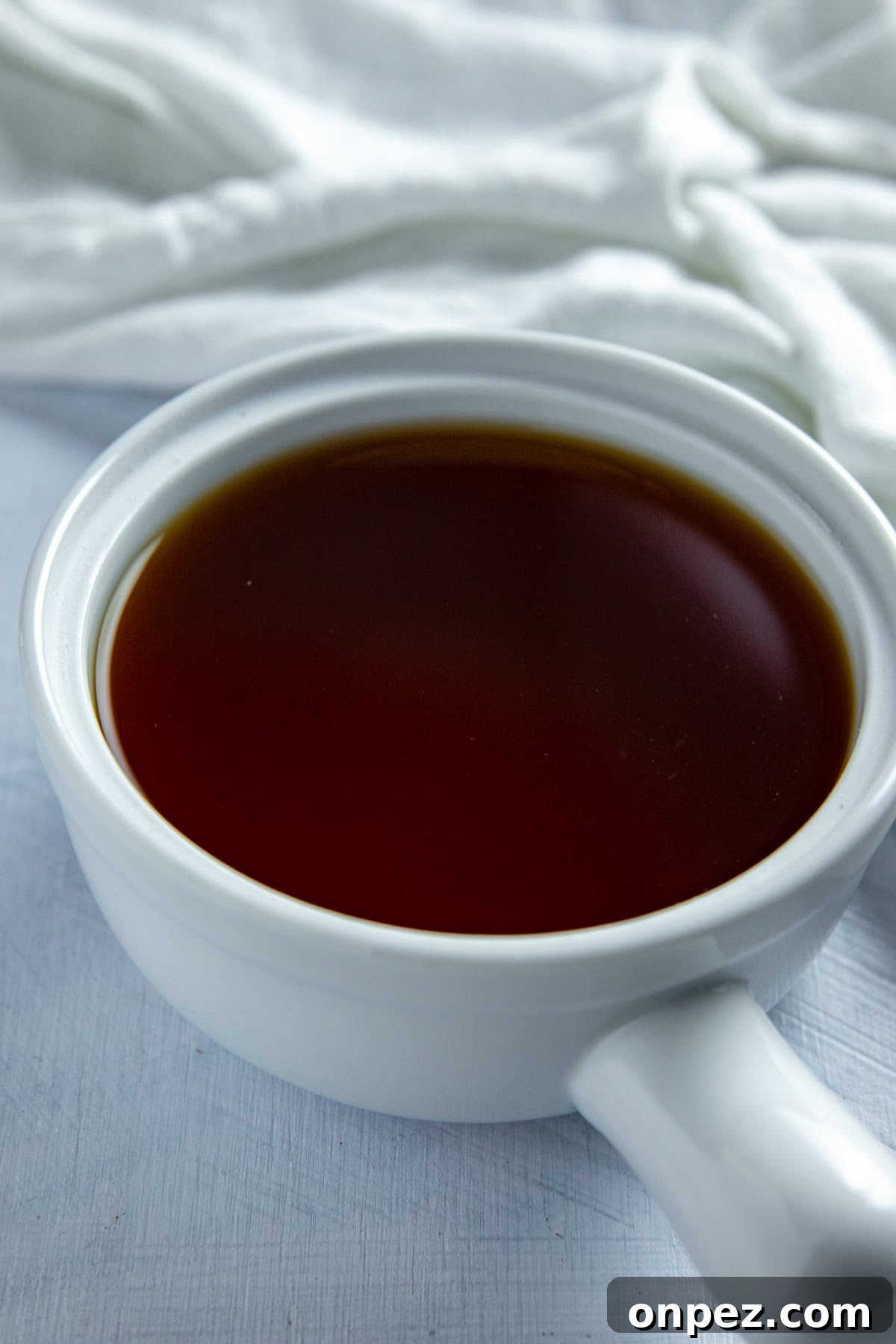 Beef broth in a small white bowl.
