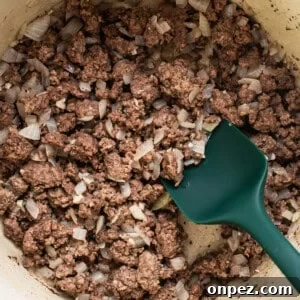 A pot filled with ground beef and onions.
