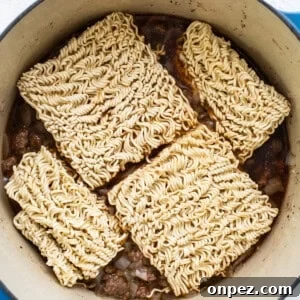 Ramen noodles in a pot on a white surface.