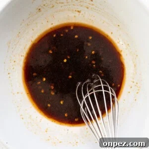 A bowl with brown liquid and a whisk.
