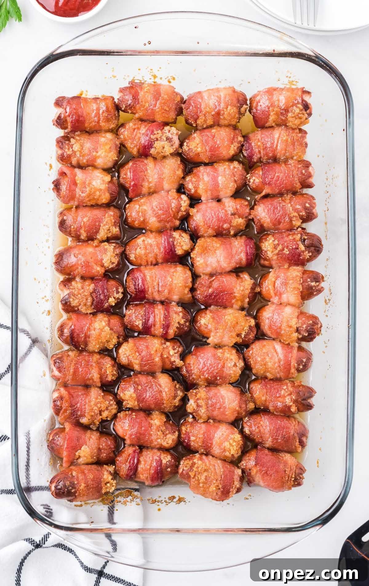 Brown Sugar Bacon-Wrapped Smokies — Crowd-Pleasing Appetizer 7 overhead shot of Bacon Wrapped Smokies staked on top of each other in a baking dish