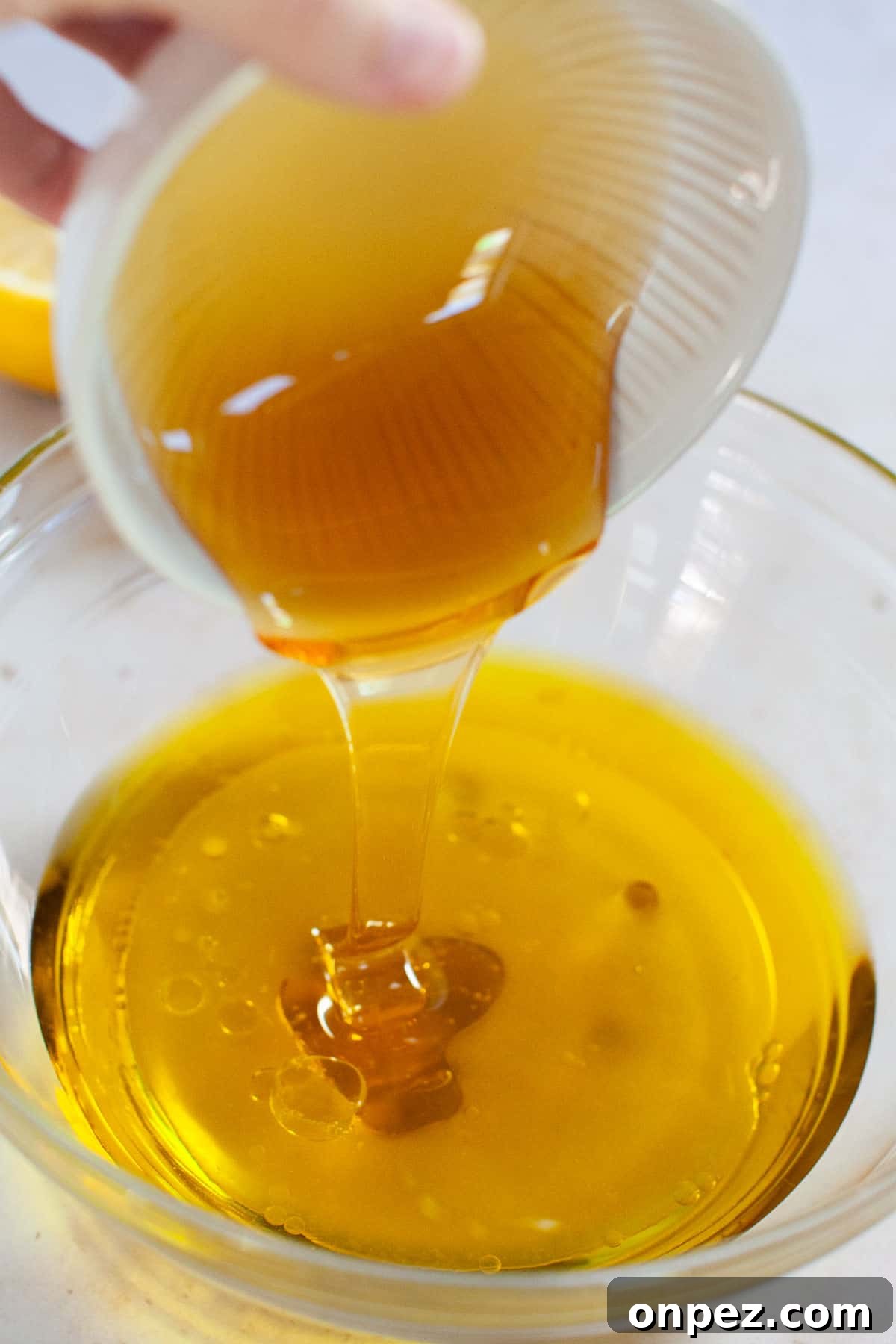 Honey being poured into a bowl with apple cider vinegar and lemon juice.
