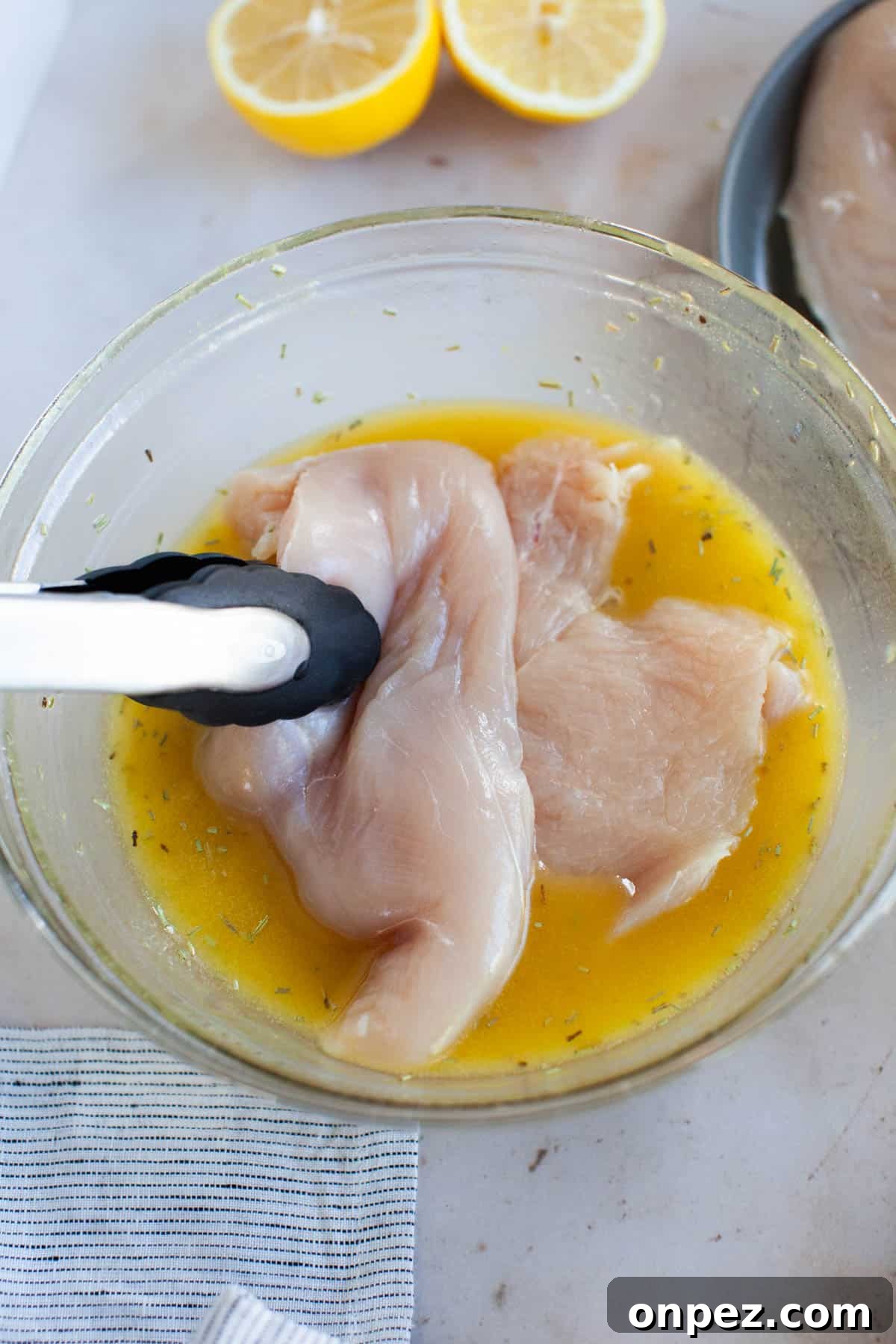 Chicken breasts being placed in bowl of honey vinaigrette marinade.