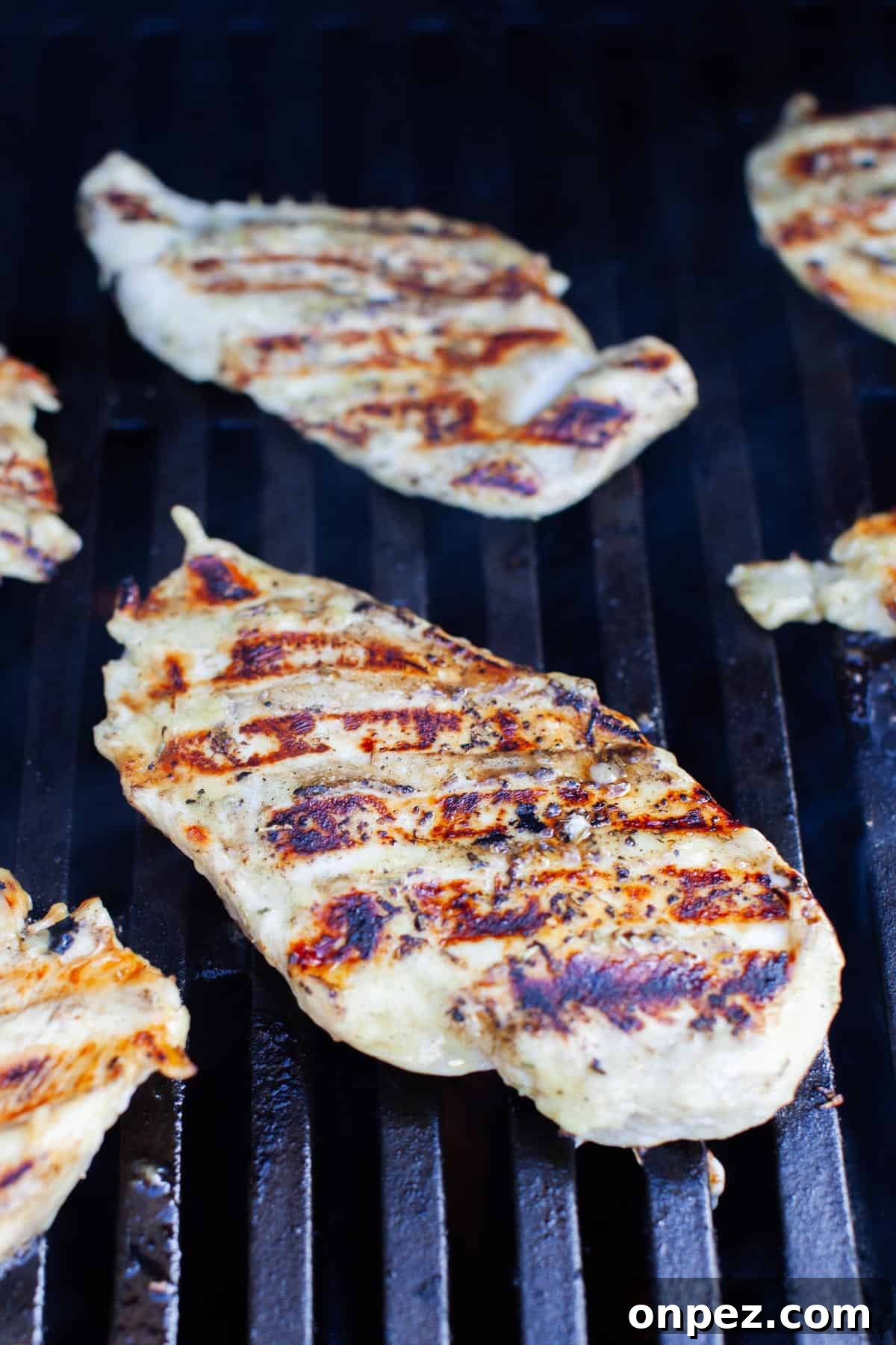 Thinly sliced chicken breast on a propane grill.