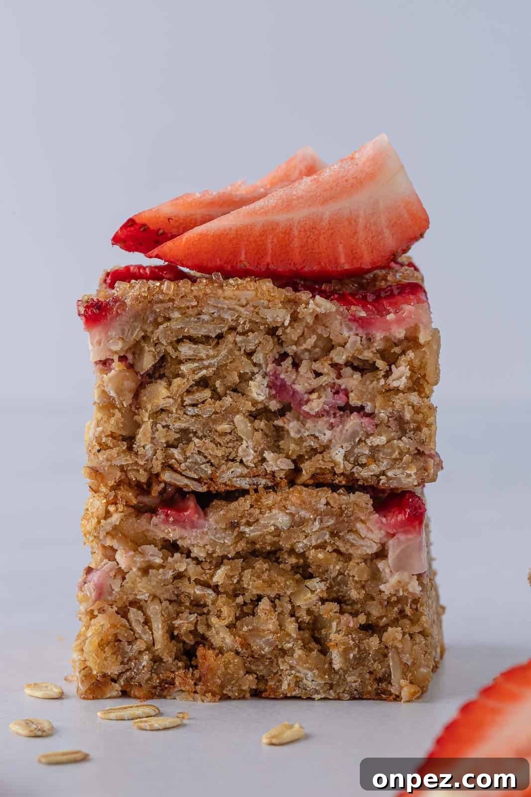 Healthy oatmeal strawberry bars stacked and topped with fresh strawberries.