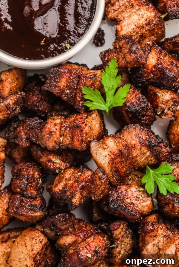 Overhead photo of crispy air fryer pork belly bites in a serving platter with BBQ dipping sauce.