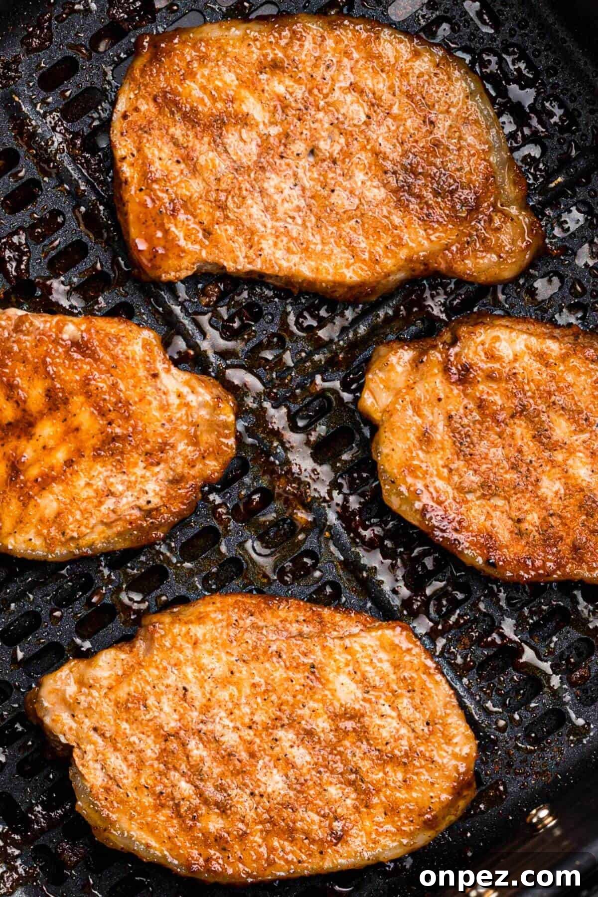 Seasoned frozen pork chops in the air fryer after being cooked.