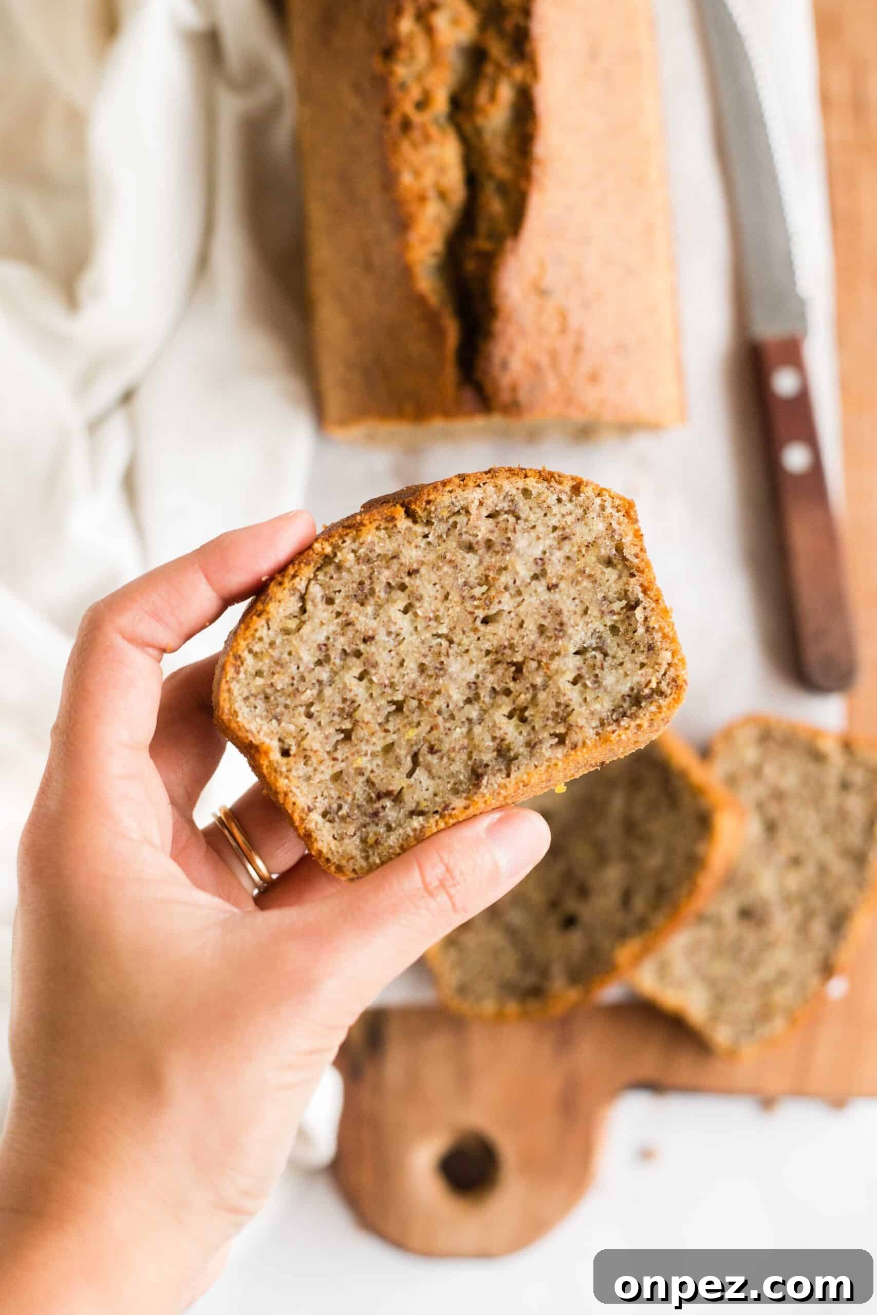 Easy Flaxseed Bread (Gluten-Free, Dairy-Free) Hand holding up a slice of flaxseed bread from a board.