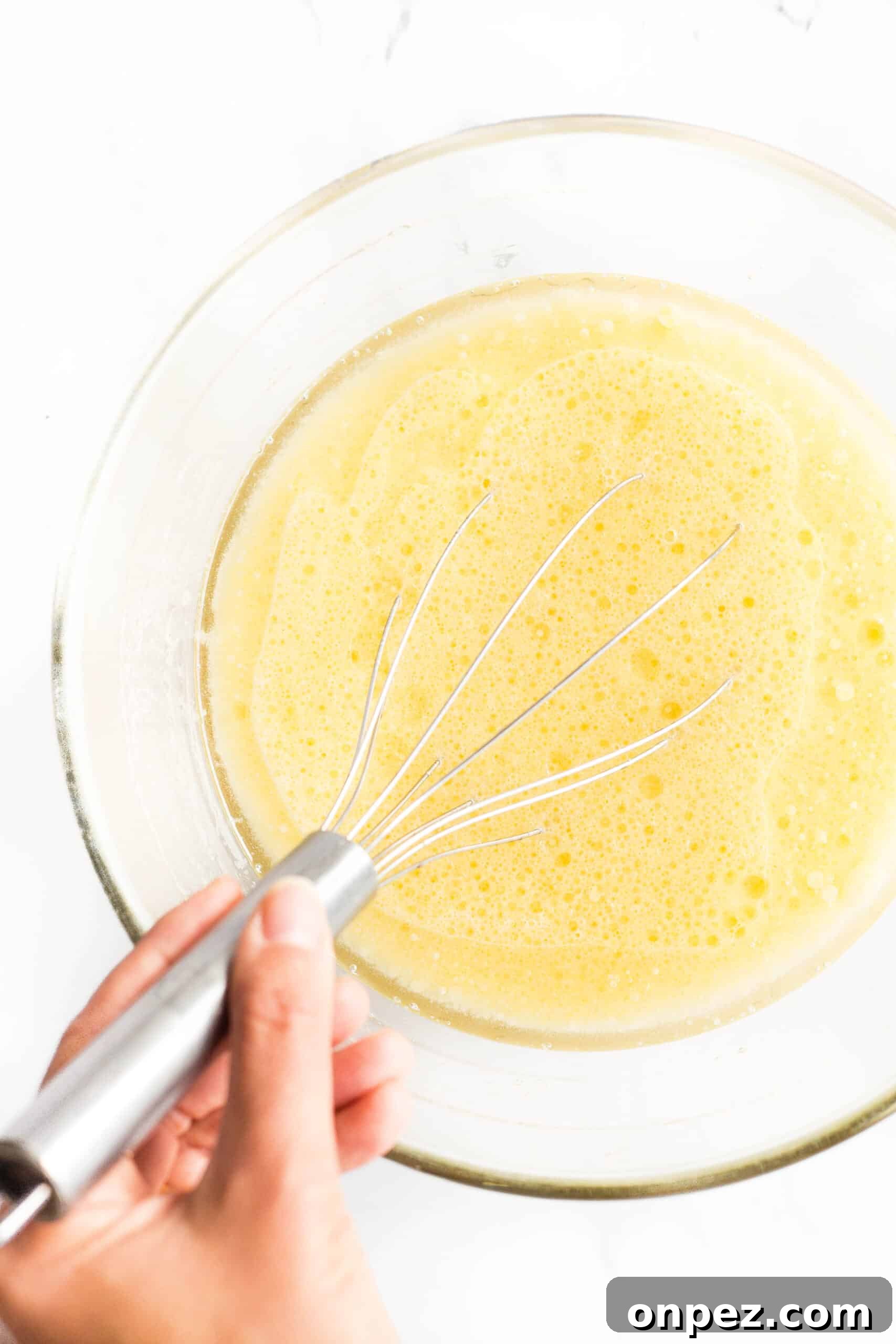 Bread Recipe with Flaxseed Meal (Gluten-Free, Dairy-Free) Whisking pale yellow liquid mixture in a glass bowl.