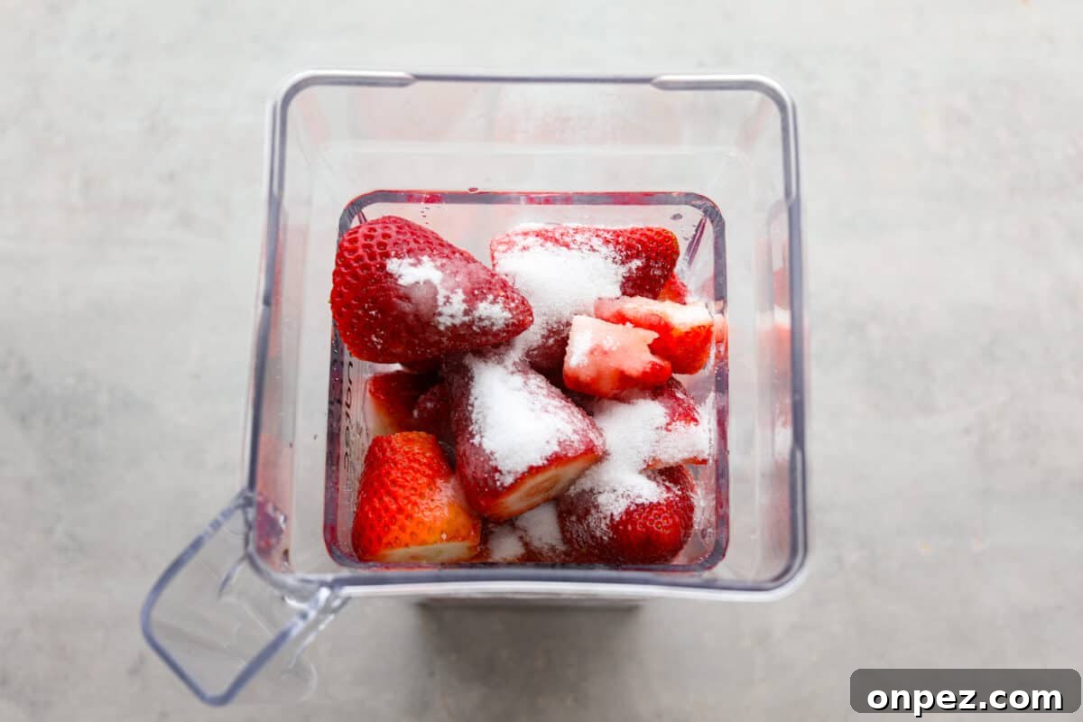 Add strawberries, sugar, and lemon juice to a blender. Process photo of the strawberries, sugar, and lemon juice added to a blender.