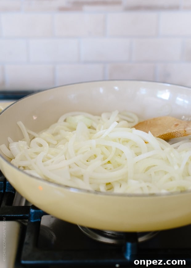Caramelizing slices of yellow onions in a pan.