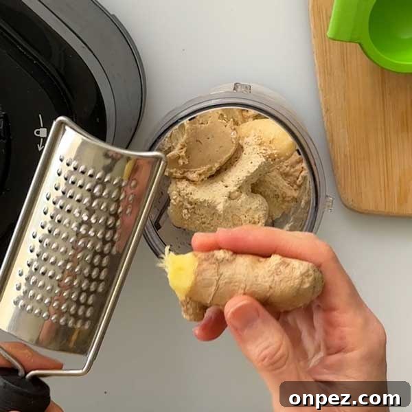 Grating fresh ginger into the smoothie cup.