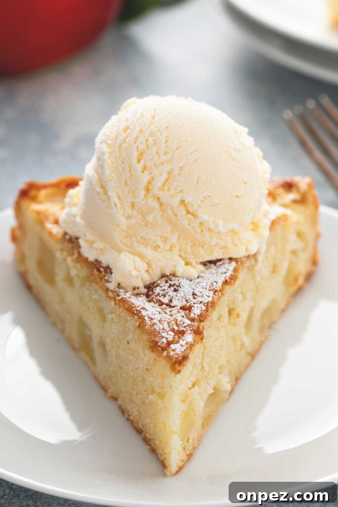 Slice of fresh apple cake served with ice cream on a white plate.