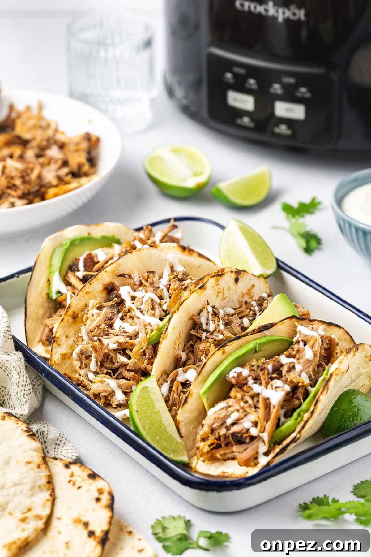 A platter of four tortillas containing shredded slow cooker carnitas.