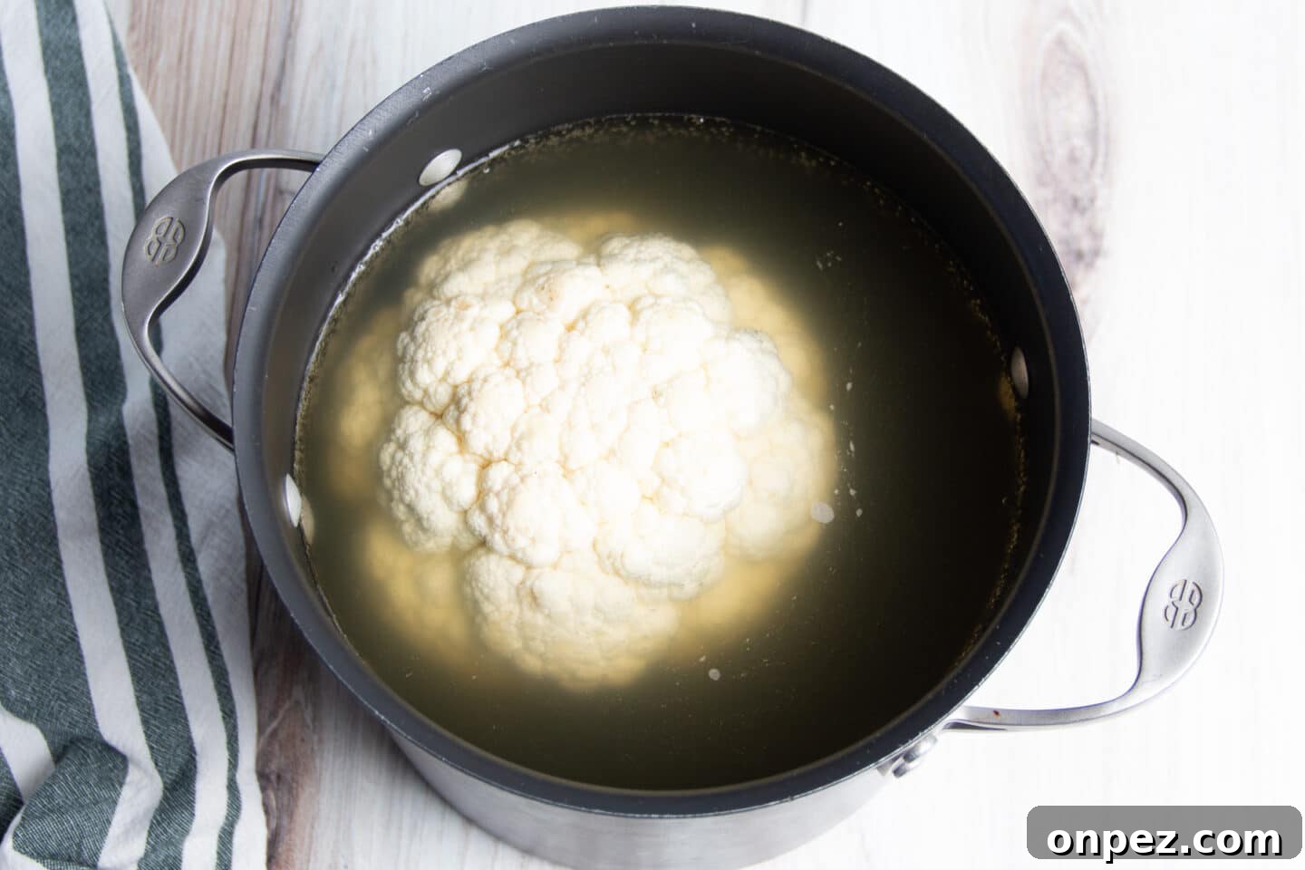 Smoked Cauliflower: How to Achieve Smoky, Tender Flavor 5 Picture of cauliflower in big pot filled with broth.