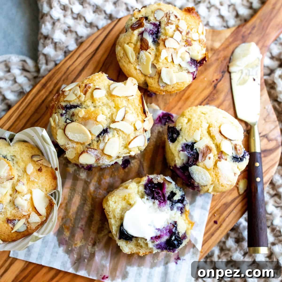 Blueberry yogurt muffins on a cutting board with a knife.