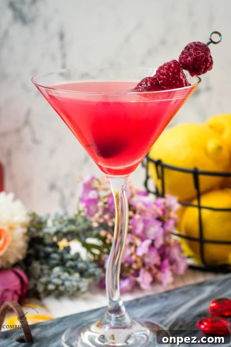 Cocktail glass filled with delicious raspberry lemon drop martini and garnished with raspberries on a cocktail spike.