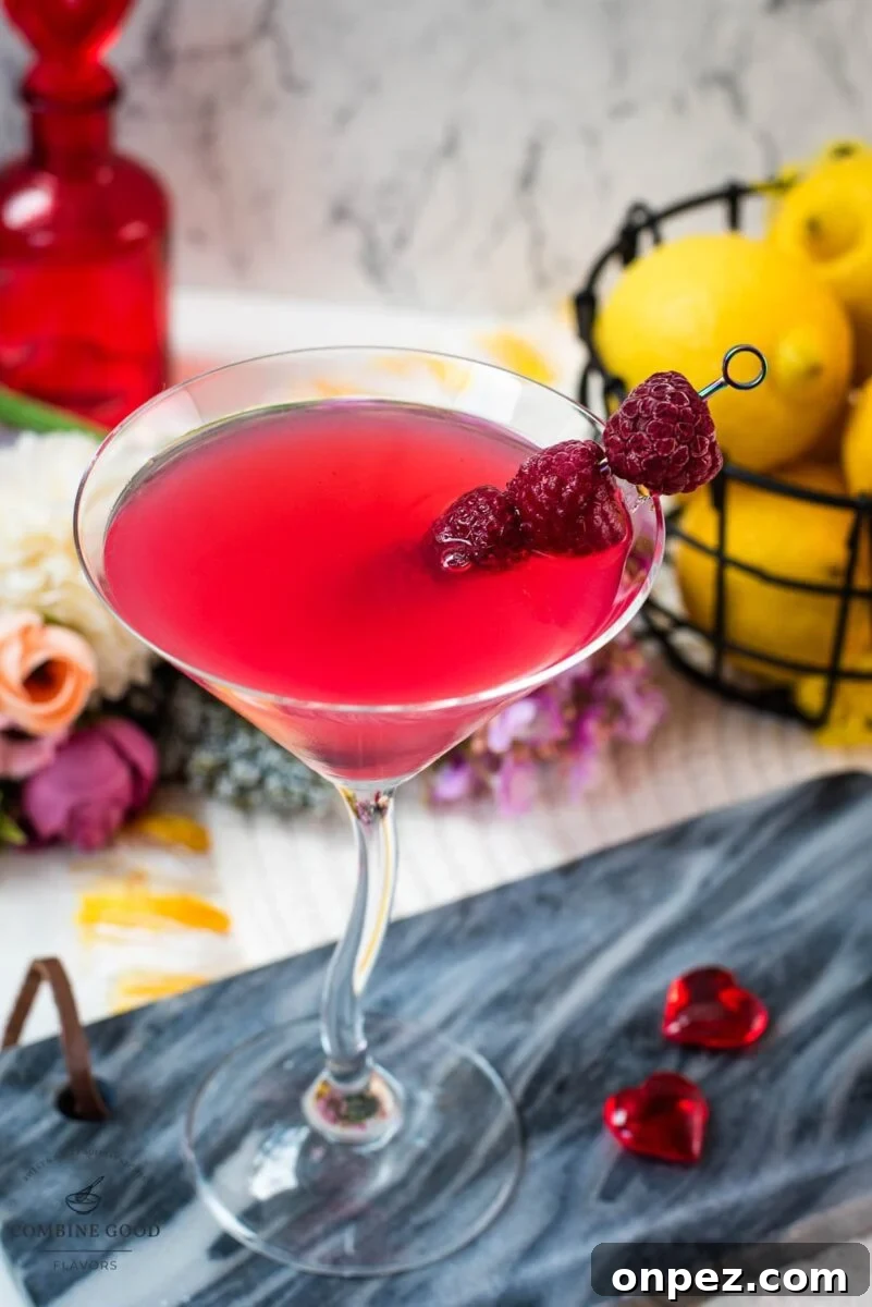 Cocktail glass filled with delicious raspberry lemon drop martini and garnished with raspberries on a cocktail spike.