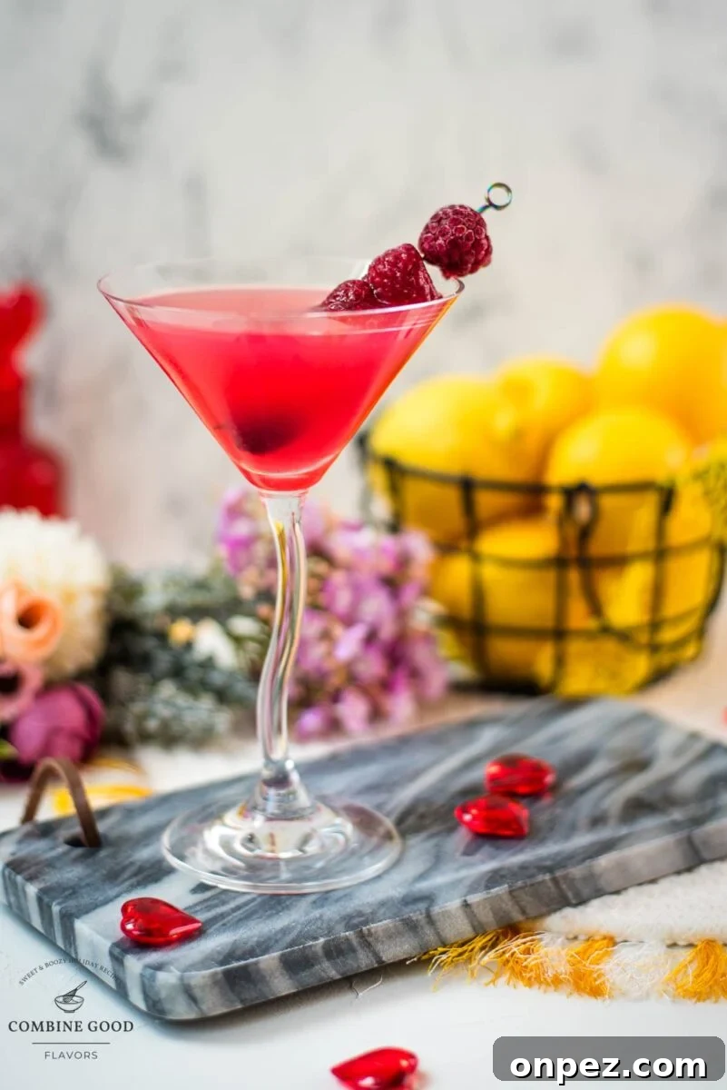 Cocktail glass filled with delicious raspberry lemon drop martini and garnished with raspberries on a cocktail spike.
