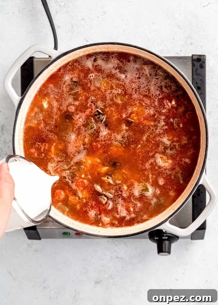 cream being poured into dutch oven with other chicken poblano soup ingredients