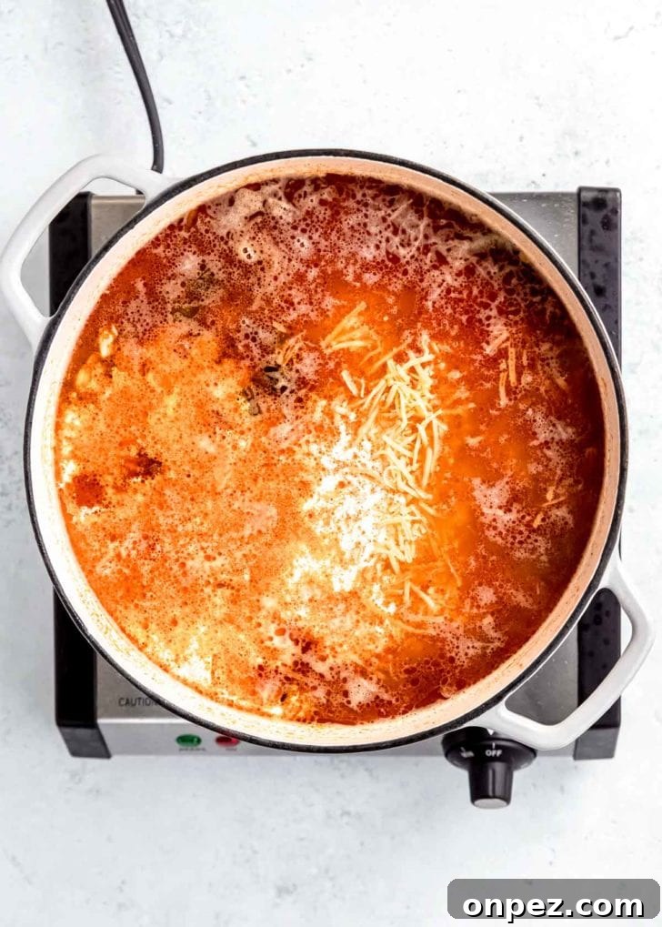 cheese being added to dutch oven with other chicken poblano soup ingredients