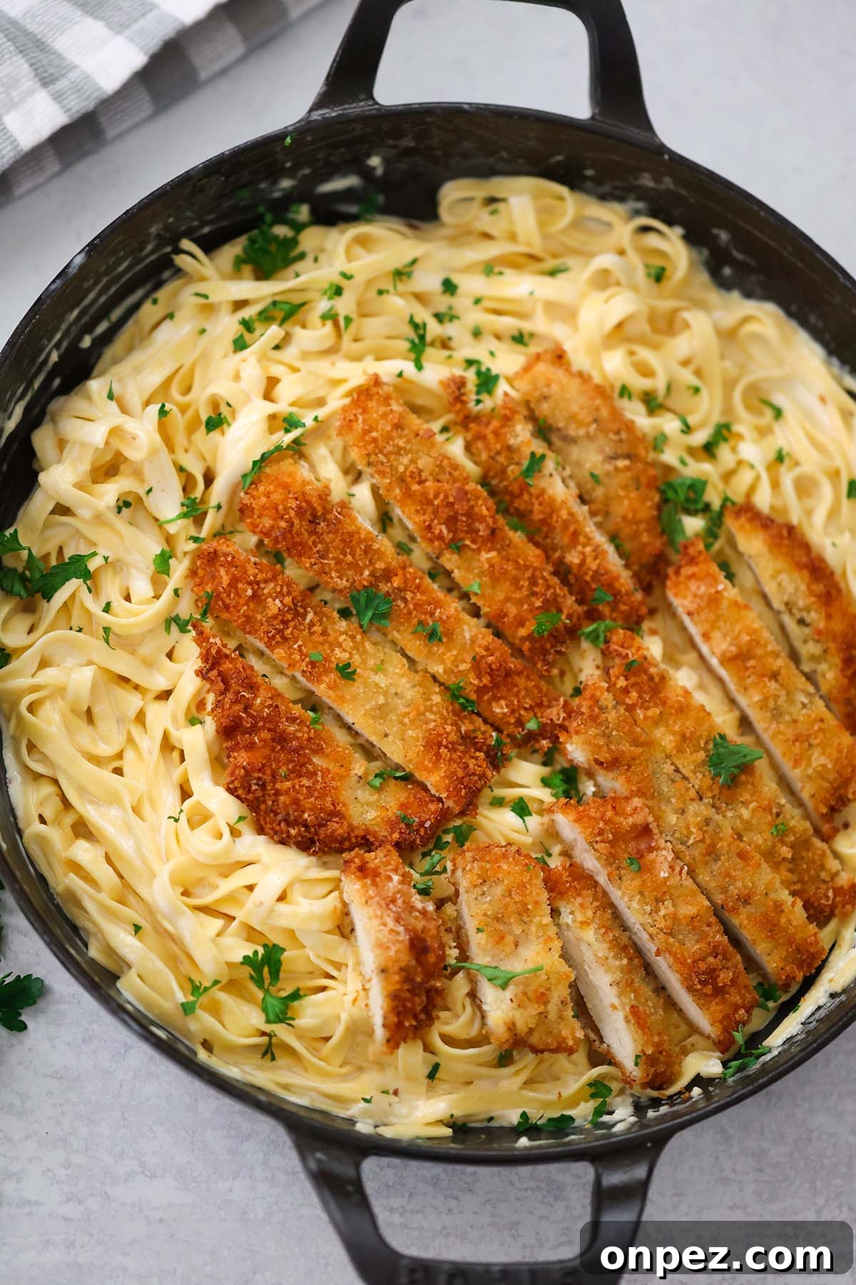 crispy chicken fettuccine alfredo in a black skillet.