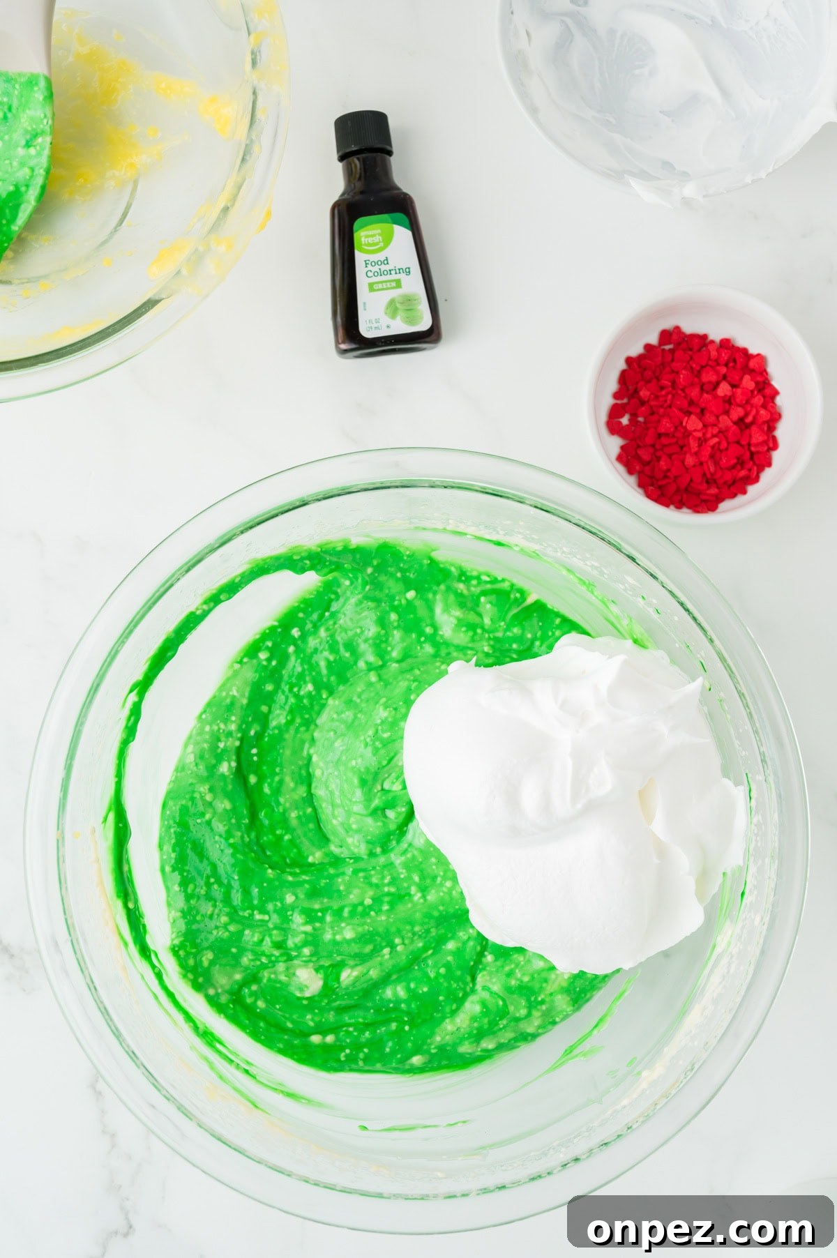 Creamy Grinch Dip Recipe for Holiday Parties 7 An overhead image of adding cool whip to the mixture.