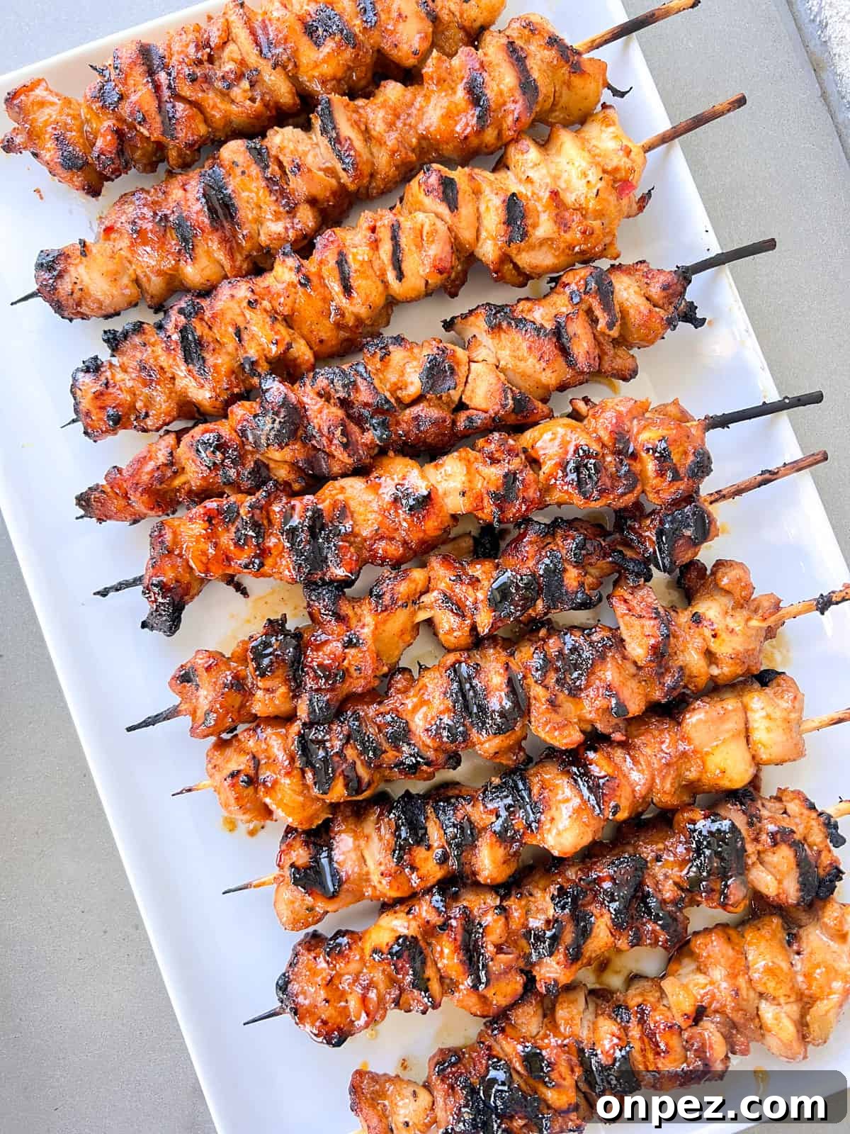 Grilled chicken skewers on white plate.