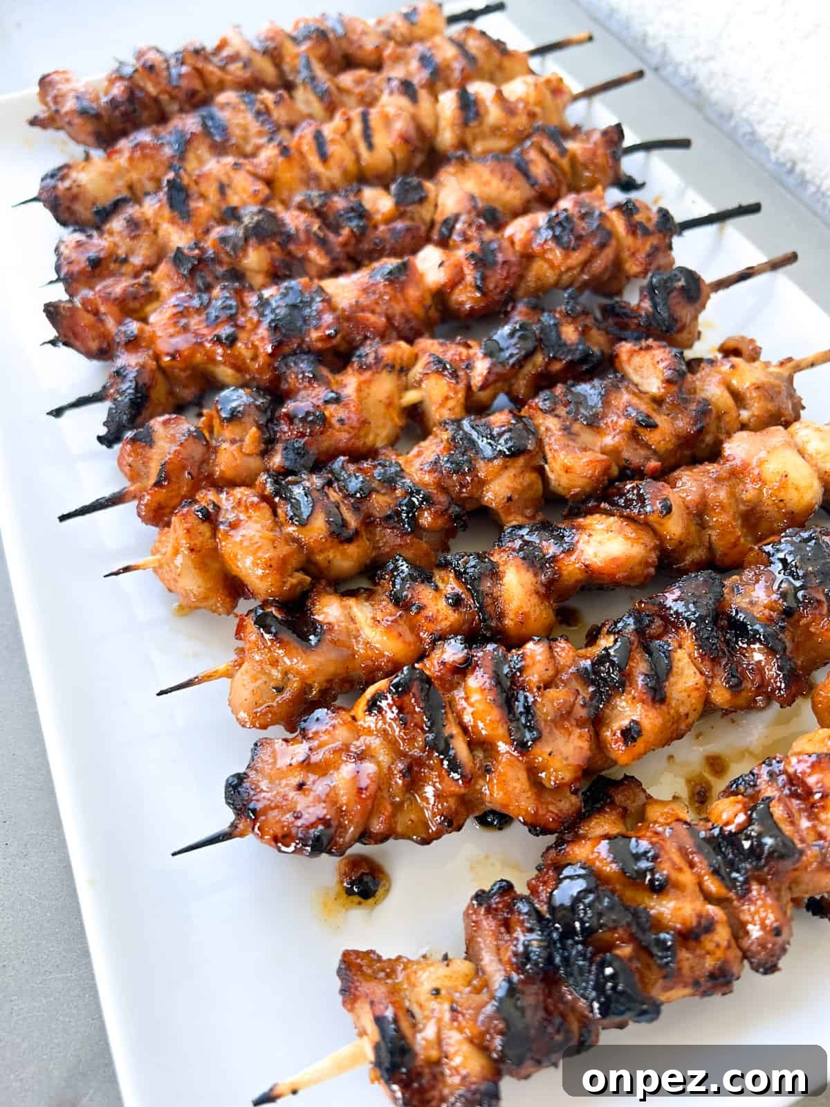 Grilled chicken thigh kabobs on skewers on a plate.