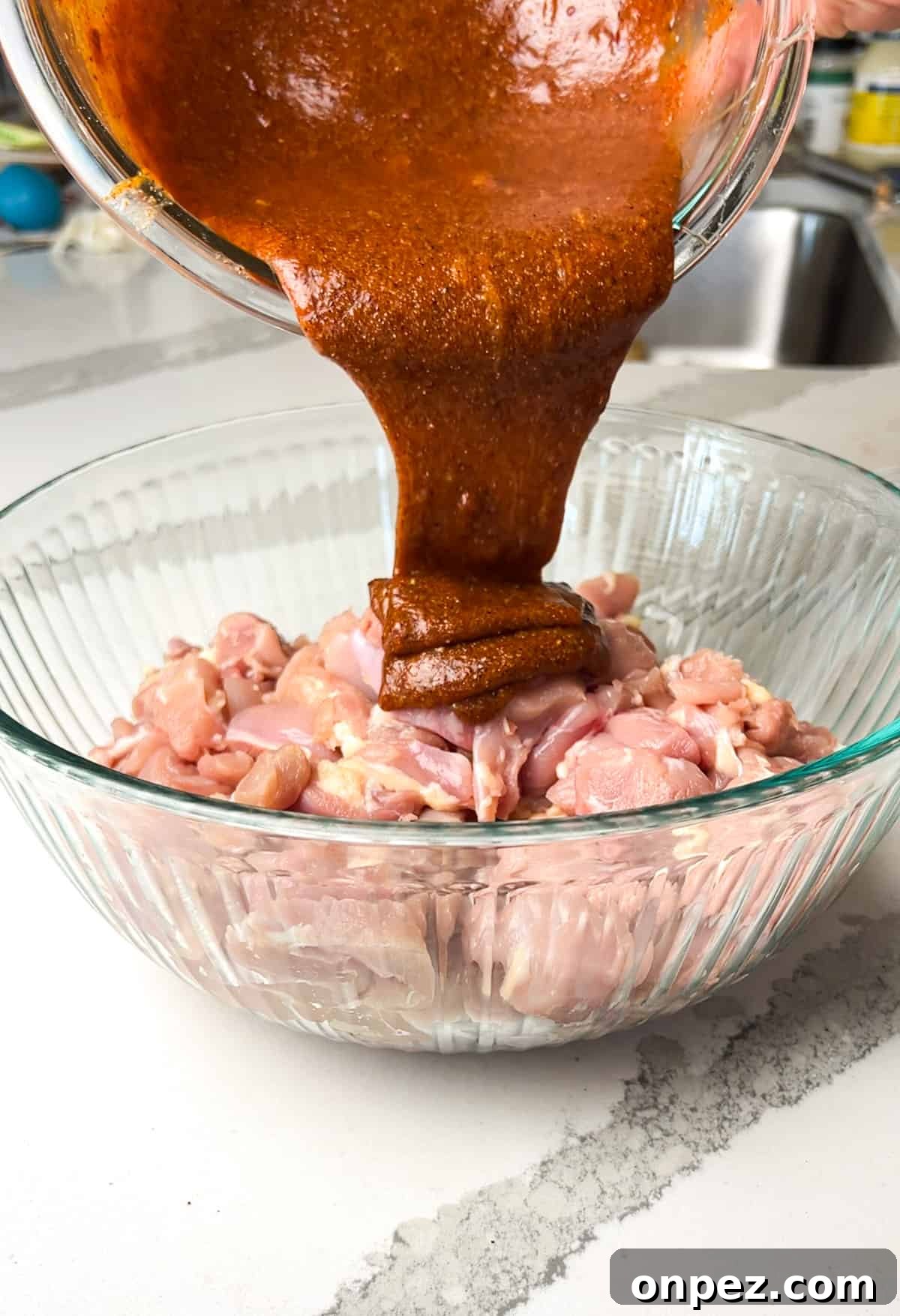 Chicken marinade being poured over chicken thighs.