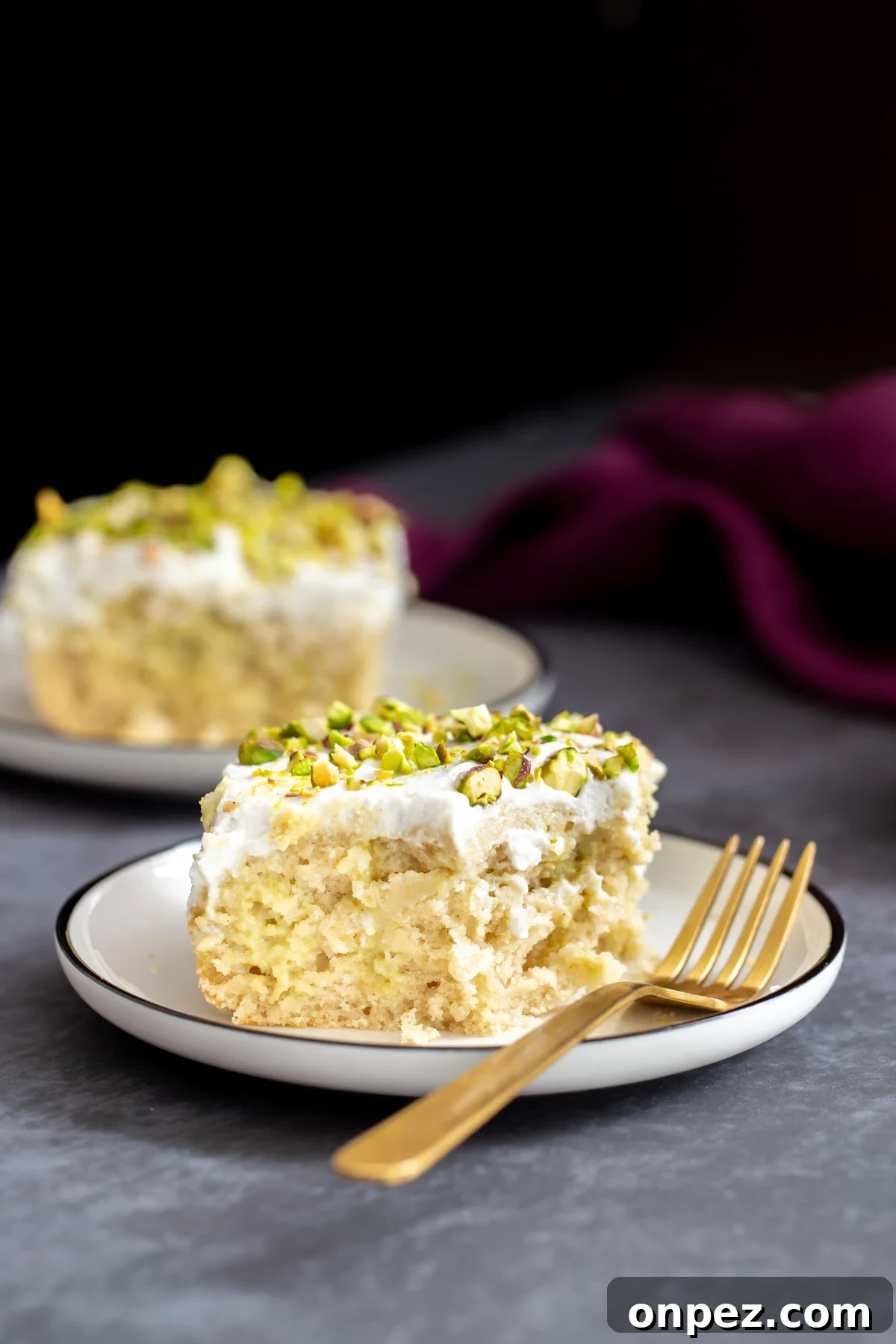 two slices of vegan ras malai tres leches cake on a grey table