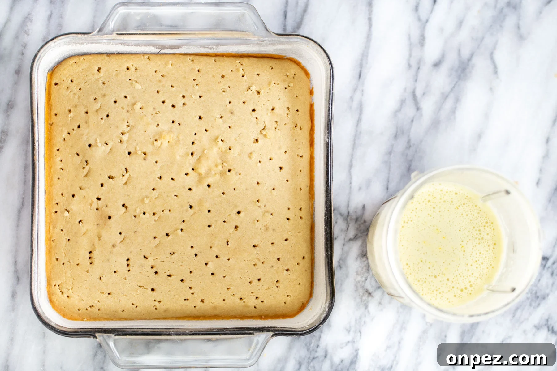 nut milk mix in a blender container next to a baked tres leches sponge